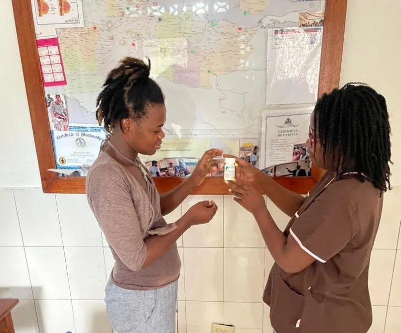 A GAHDA nurse handing medication to a patient at the clinic in Jérémie